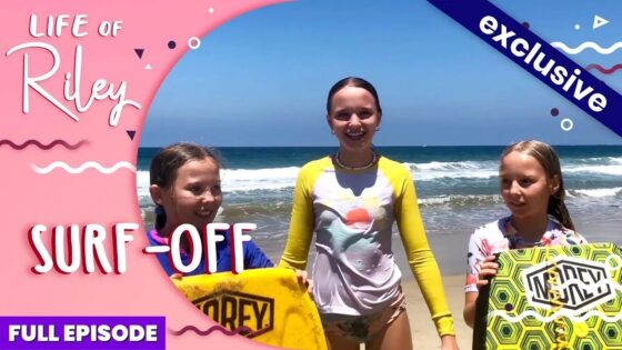 Thumbnail for a video: three kids on a sunny beach with surfboards, overlaid with 'Life of Riley' and 'Surf Off' text and an 'Exclusive' badge.