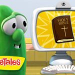 Green VeggieTales character smiles at a computer monitor showing a Bible illustration on a yellow sunburst background.