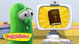 Green VeggieTales character smiles at a computer monitor showing a Bible illustration on a yellow sunburst background.