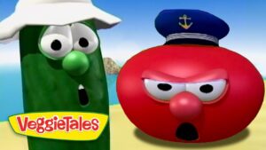 Green cucumber character with a white hat and surprised expression beside a red tomato character wearing a captain's hat on a beach, VeggieTales logo visible.