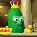 Animated green cucumber with a yellow crown, looking concerned in a castle interior beside two ducklings, from VeggieTales logo visible nearby