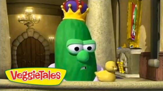 Animated green cucumber with a yellow crown, looking concerned in a castle interior beside two ducklings, from VeggieTales logo visible nearby