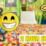 Man in cowboy attire sits in a colorful ball pit with oversized smiley overlays and a bold '2 HOUR SPECIAL' banner nearby.