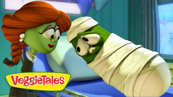 Green veggie dressed as a mummy leans in to kiss a red‑haired veggie; VeggieTales logo in bottom left.