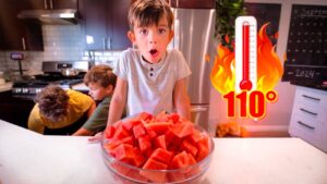 A boy leans toward a bowl of watermelon on a kitchen island with a surprised expression; two other kids in the background, and a flame icon with a thermometer reading 110° to the right.