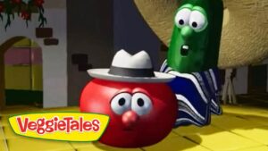 Red tomato character with a gray hat and surprised eyes sits on a yellow floor while a green cucumber in a striped robe looms behind in a VeggieTales scene, logo in the corner.