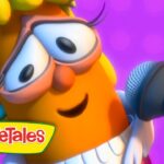 Cartoon orange veggie with glasses singing into a microphone on a purple stage, VeggieTales logo visible.