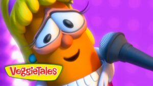 Cartoon orange veggie with glasses singing into a microphone on a purple stage, VeggieTales logo visible.