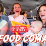 Four friends and a baby in a car, laughing as they eat burgers with an In-N-Out sign and 'Food Coma' text overlay.