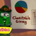 Green VeggieTales character in a hat points to a page titled 'Charitable Giving' showing a multicolored pie chart and a downward line graph; VeggieTales logo bottom left.