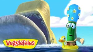 Two VeggieTales characters ride in a yellow raft on bright blue water, a tall green veggie wearing glasses beside a small yellow duck, with the VeggieTales logo in the corner.