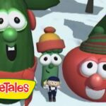 Three VeggieTales characters—a tall cucumber, a small green bean, and a red tomato with hats—pose in a snowy scene with a tiny man in front and the VeggieTales logo.