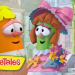 Two VeggieTales characters converse on a sunny cartoon street; a green veggie in a pink dress and hat holds a colorful bouquet while an orange carrot listens. VeggieTales logo on the corner.