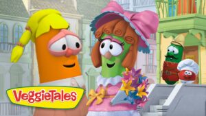 Two VeggieTales characters converse on a sunny cartoon street; a green veggie in a pink dress and hat holds a colorful bouquet while an orange carrot listens. VeggieTales logo on the corner.