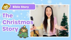 Thumbnail for a kids' Bible story video: 'The Christmas Story' with a smiling woman presenter, a guitar, and a Christmas tree in the background.