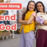Two women stand with arms crossed on a urban walkway, a bold 'Dance Along' banner and 'Friend of God' text over the image, suggesting a video thumbnail.
