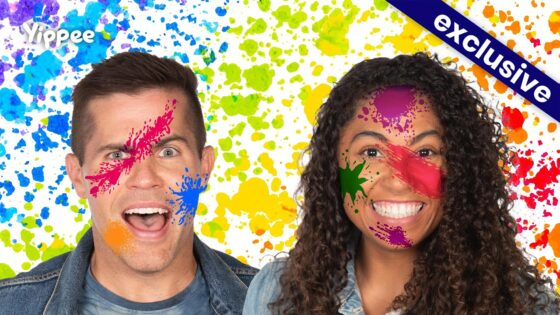 Two smiling people with colorful paint splatters on their faces against a bright splattered backdrop