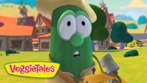 Green cucumber VeggieTales character wearing a straw hat, looking surprised in a sunny cartoon village setting.