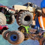 Man in a blue hard hat and orange safety vest poses beside colorful monster trucks in a dynamic collage image.