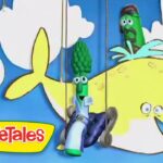 Three vegetable puppets hang on strings in front of a blue sky backdrop with a yellow whale and VeggieTales logo in the corner.