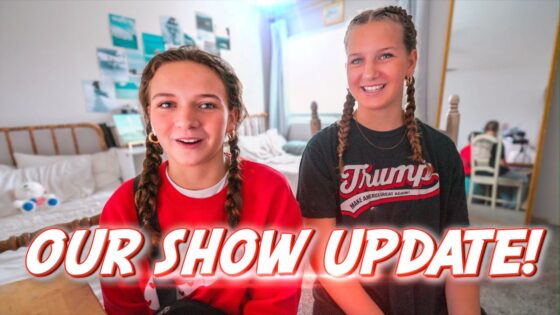 Two girls with braided hair sit in a bright bedroom, smiling at the camera with the bold 'OUR SHOW UPDATE!' text overlaid across the bottom area.