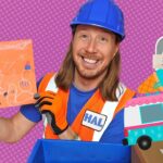 Construction worker in a blue hard hat and orange safety vest holds up a child's orange drawing, with a colorful cartoon van and mailbox in the background.