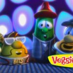 Four cartoon vegetables in hats and outfits pose on a stage with blue-purple lights, VeggieTales logo in the corner.