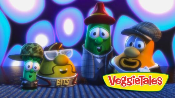 Four cartoon vegetables in hats and outfits pose on a stage with blue-purple lights, VeggieTales logo in the corner.