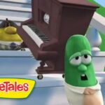 VeggieTales scene with a green vegetable character looking surprised as a brown piano is rolled up stairs, logo VeggieTales in the corner.