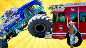 Blue monster truck tilts toward a red fire truck while a man in a cowboy hat smiles beside them against a bright yellow sunburst background, creating a playful stunt scene.