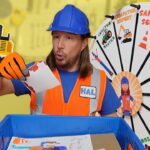 Construction worker in safety vest and blue hard hat places a drawing into a blue bin, with a colorful wheel backdrop behind him.
