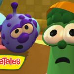 Green vegetable with an orange cap and wide-eyed, surprised expression beside a purple speckled veggie in a colorful VeggieTales set (logo bottom left).