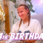 Girl with braided hair smiling at a birthday party, balloons in the background and a '14th Birthday!' overlay text.