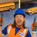Construction worker in a blue hard hat and orange safety vest points upward with 'Before' and 'After' school buses in the background on a gravel surface.