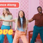 Five diverse people dancing in a pink room; banner reads 'Dance Along' and a yellow 'Love' graphic on the screen.
