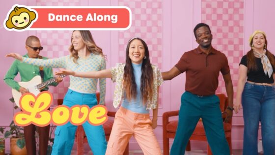 Five diverse people dancing in a pink room; banner reads 'Dance Along' and a yellow 'Love' graphic on the screen.