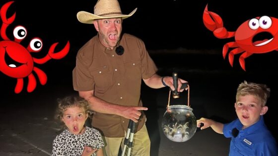 Man wearing a tan cowboy hat and brown shirt at night on a beach, holding a lantern with two children beside him, red cartoon crabs on the sides.