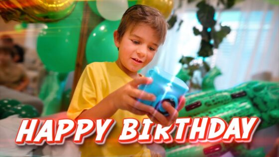 Young boy in a yellow shirt celebrates a birthday, holding a blue toy with green balloons and party decorations behind him; a 'HAPPY BIRTHDAY' banner is across the bottom.