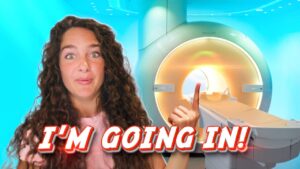 YouTuber with curly hair gestures toward a large MRI scanner, overlaid with the caption "I'M GOING IN!"