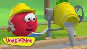 Red VeggieTales tomato wearing a yellow hard hat reads a book beside a cement mixer on a construction site.