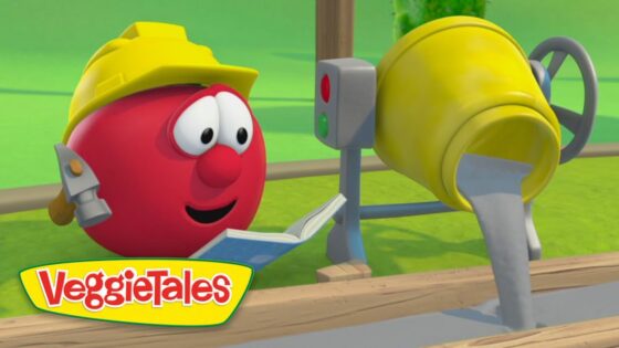 Red VeggieTales tomato wearing a yellow hard hat reads a book beside a cement mixer on a construction site.
