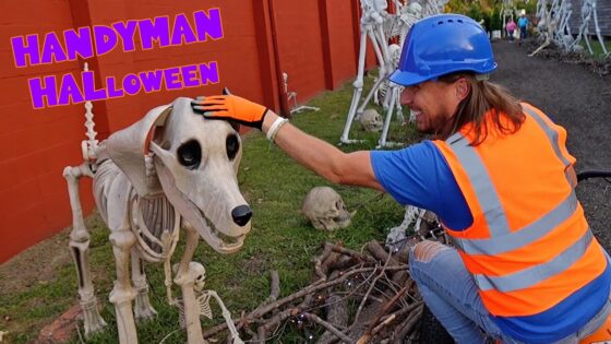 Man in an orange safety vest and blue helmet pets a life-size skeleton horse in a Halloween display by a red wall.