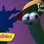 Green veggie with a yellow hat looks at a pink poster on a purple wall; VeggieTales 'Tales from the Crisper' title visible in the corner.