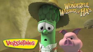Animated VeggieTales scene: a green cucumber and a pink pig look surprised, wearing a hat, with 'The Wonderful Wizard of Ha's' logo in the corner.