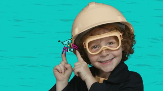 Smiling child wearing a hard hat and safety goggles, pointing at a cartoon crab on their finger against a turquoise background.
