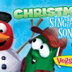 Cartoon red snowman with a blue hat and carrot nose posing with a green veggie wearing a plaid hat; 'Christmas Sing-Along Songs!' VeggieTales background