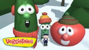 Three VeggieTales characters—a tall green cucumber, a red tomato, and a small green bean—wear winter hats in a snowy landscape, with a VeggieTales logo in the corner.