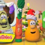 Three VeggieTales characters in holiday outfits celebrate in a festive living room with a Christmas tree and stockings.