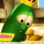Green VeggieTales character wearing a crown leans toward a small yellow duckling in shallow water, with a cheerful expression.