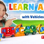 Smiling woman pointing at a row of colorful toy vehicles forming the ABCs in a bright outdoor scene, for a kids' learning video.